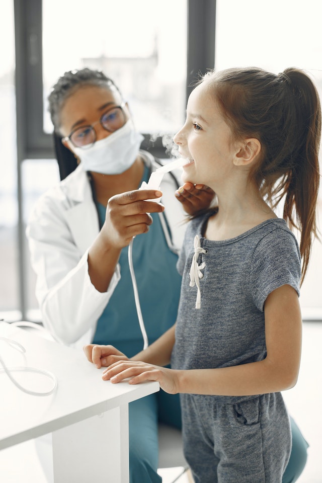 nurse helping asthmatic wheezing girl with nebuliser